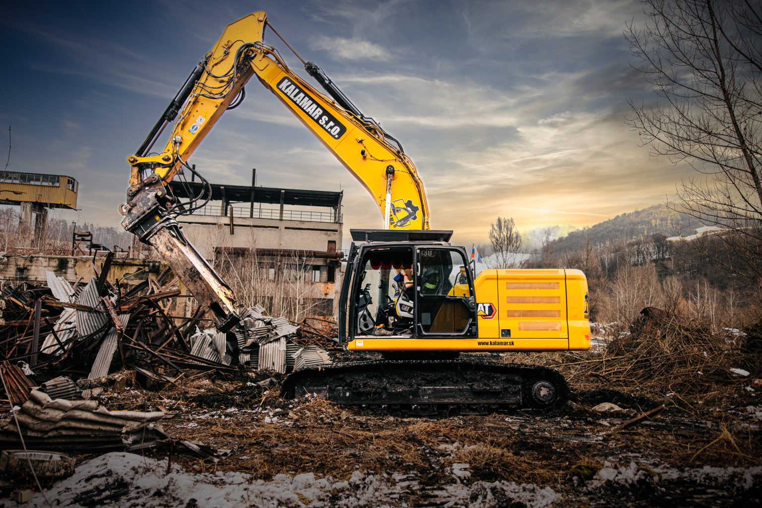 Pásové rýpadlo Caterpillar 330 s demolačnou nožnicou počas demolácie priemyselného areálu