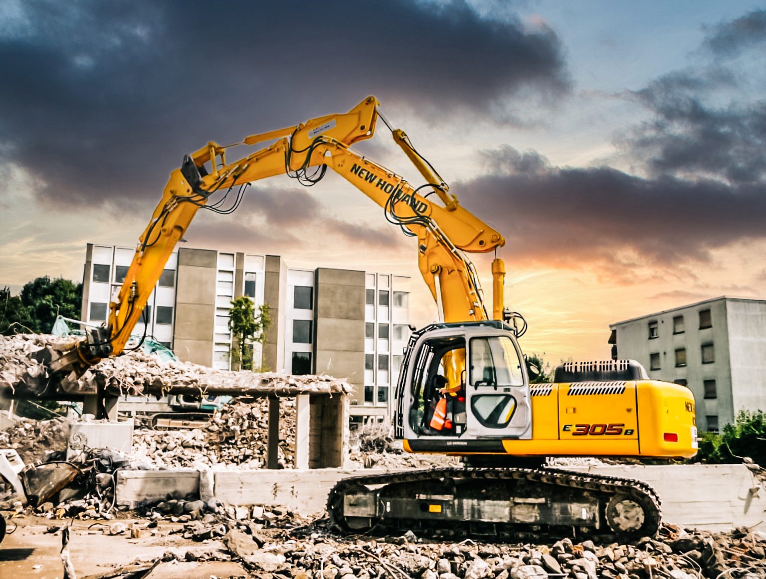 Pasové rýpadlo New Holland E 305 B počas demolácie obytnej budovy v zastavanej časti mesta